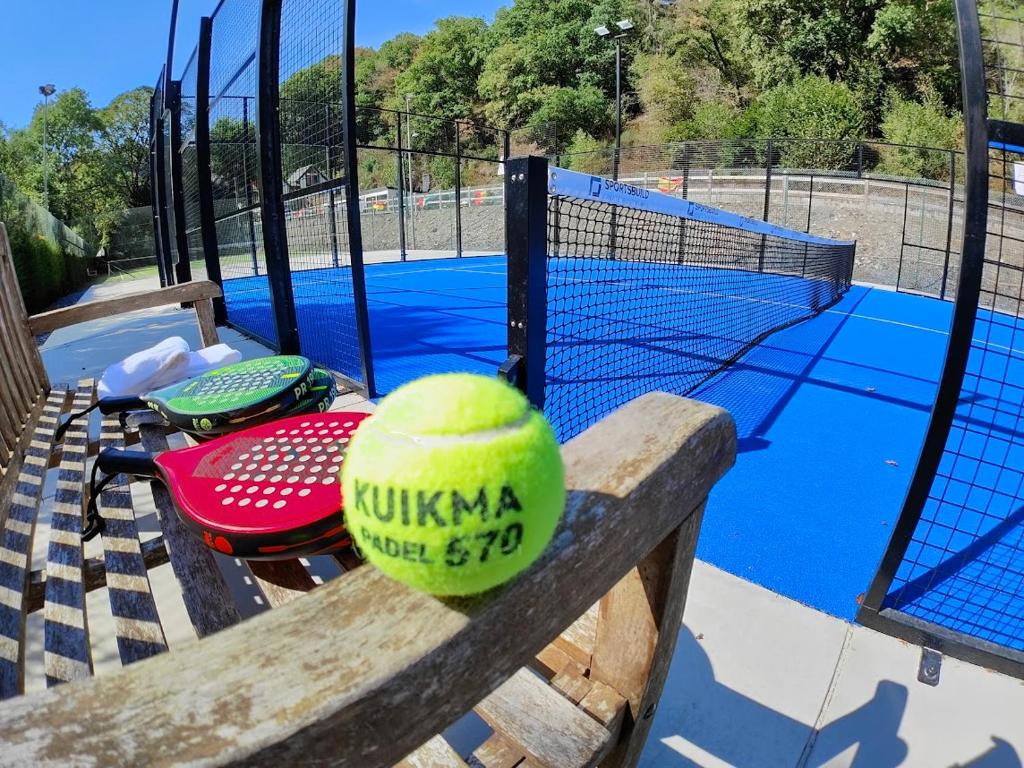 a tennis ball is sitting on a bench next to a tennis court at Cocoon Hotel Belair in Bourscheid