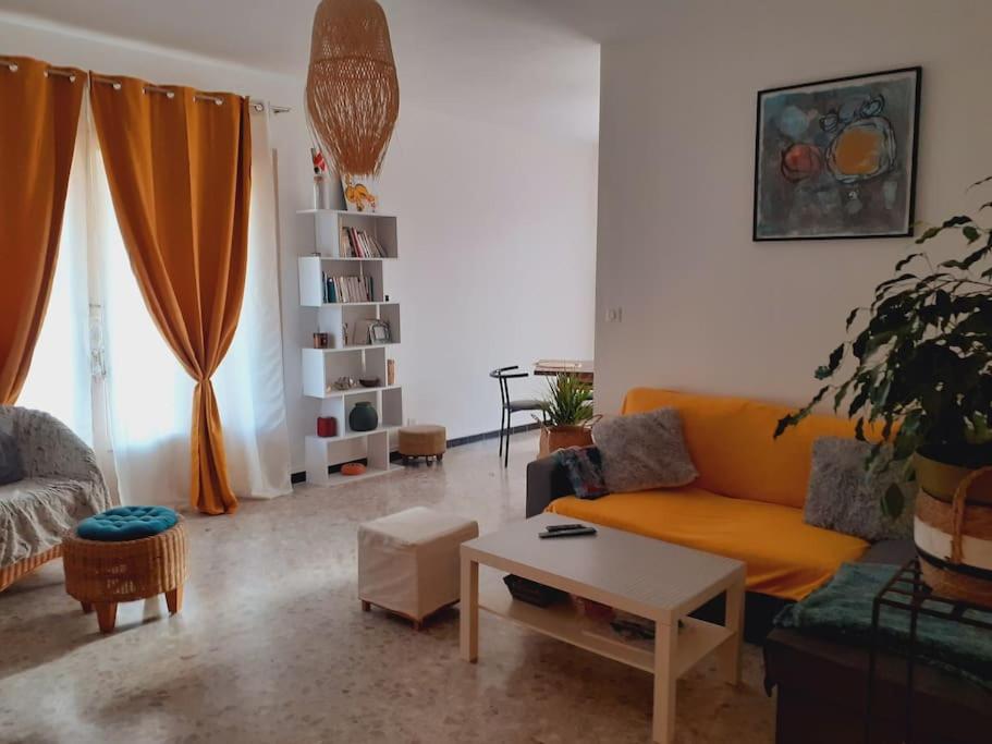 un salon avec un canapé orange et une table dans l'établissement Escapade confort chez Mel à Avignon, à Avignon