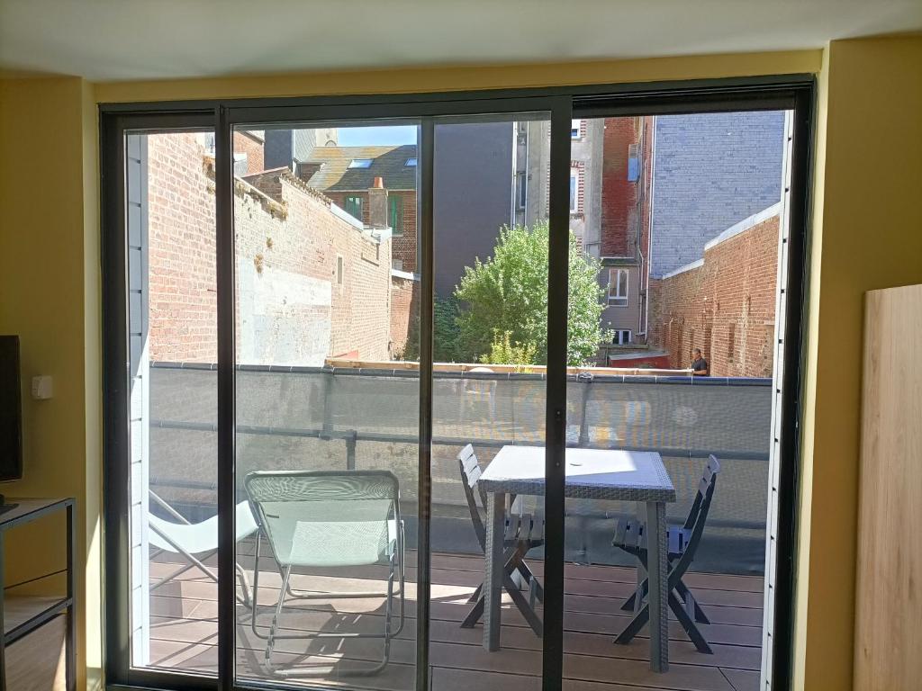 a sliding glass door with a table and chairs on a balcony at Studio à 2 pas de la plage avec terrasse in Mers-les-Bains