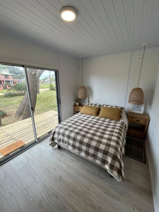 a bedroom with a bed and a large window at Nina casa de playa in Balneario Buenos Aires