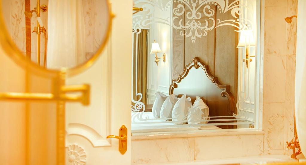 baño con espejo y cama con almohadas blancas en Bishrelt Hotel en Ulán Bator