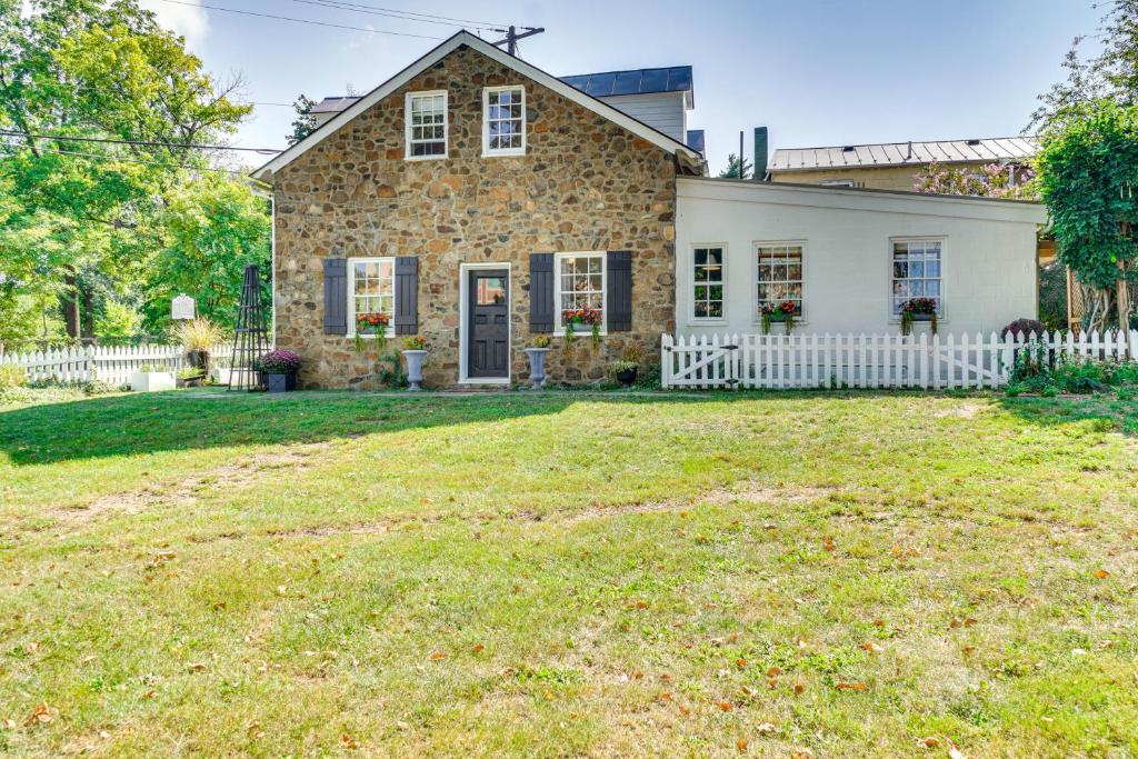 una casa in pietra con una staccionata bianca e un cortile di Cottage with Furnished Patio and Garden Dtwn Leesburg a Leesburg