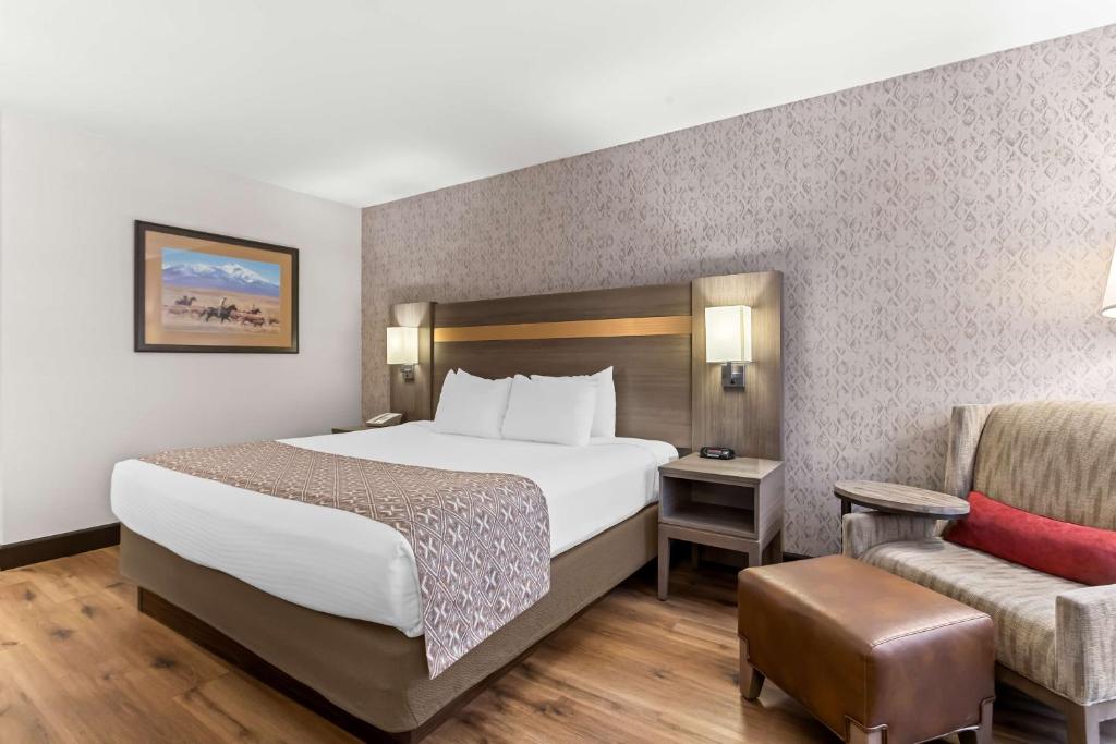 a hotel room with a bed and a chair at Best Western Moriarty Heritage Inn in Moriarty