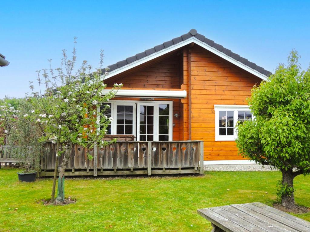 a small wooden house with a fence and trees at ZeeWolf in Sint Annaland