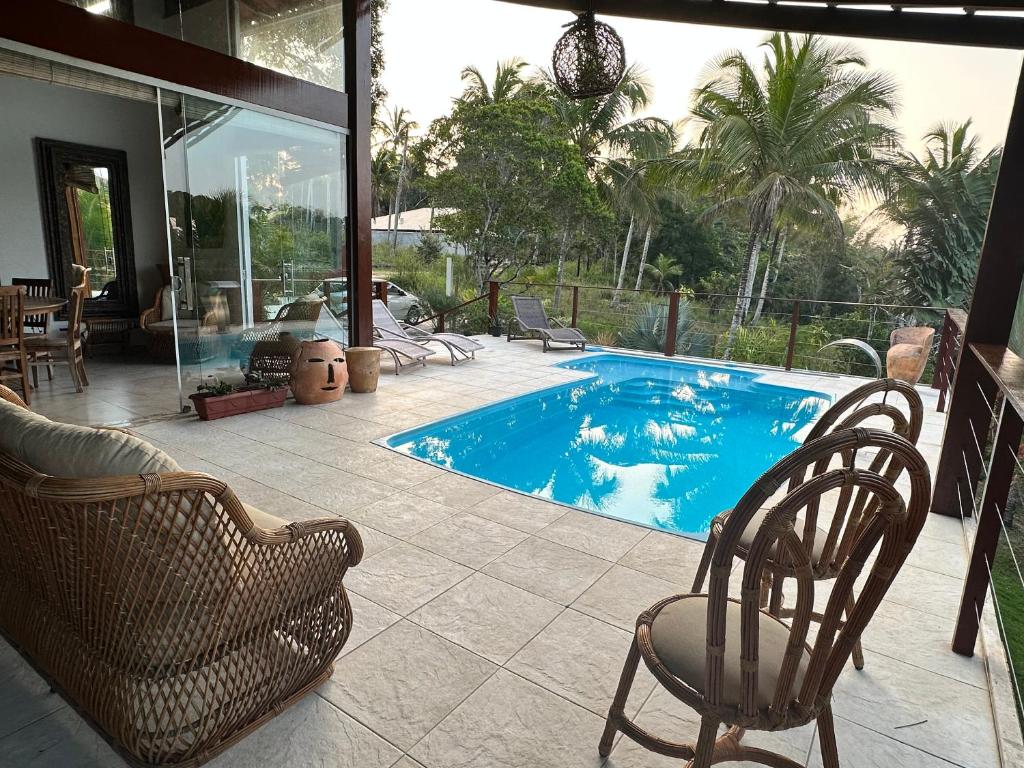 Casa Dendê - Arraial D'Ajuda في ارايال دايودا: حمام سباحة مع كرسيين وطاولة