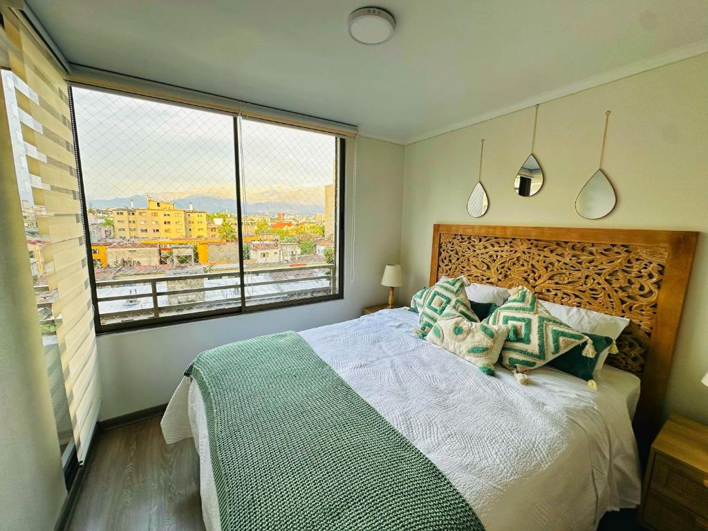 a bedroom with a large bed and a large window at Departamentos Real in Santiago