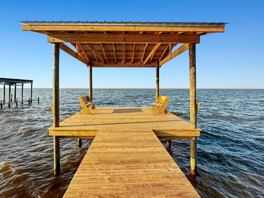 a wooden pier with two chairs on the water at Baywatch Paradice Bayfront, private pier, Sleeps 8 Fenced Dog Area 8 m to beach in Gulf Shores