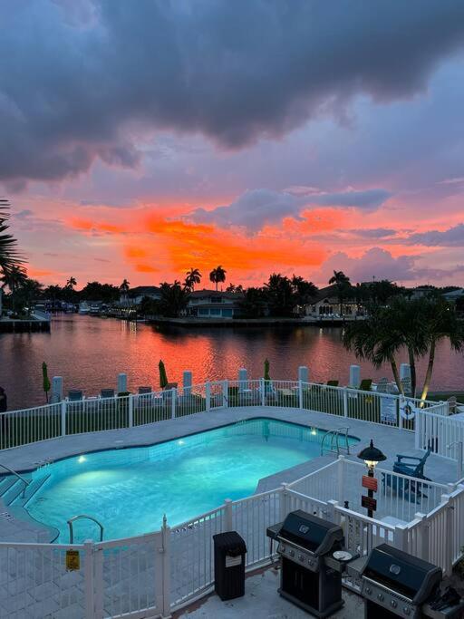 a swimming pool in front of a river with a sunset at Aloha Apartments On the Intracoastal-Walk to the Beach in Pompano Beach