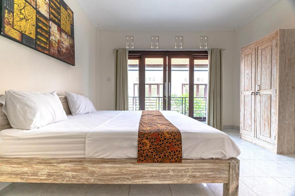 a bedroom with a large bed with a wooden bench at Azalea Homestay & Villa in Canggu