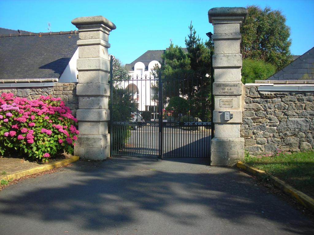 a gate with pink flowers in front of a house at Les Terrasses De La Comtesse in Saint-Quay-Portrieux