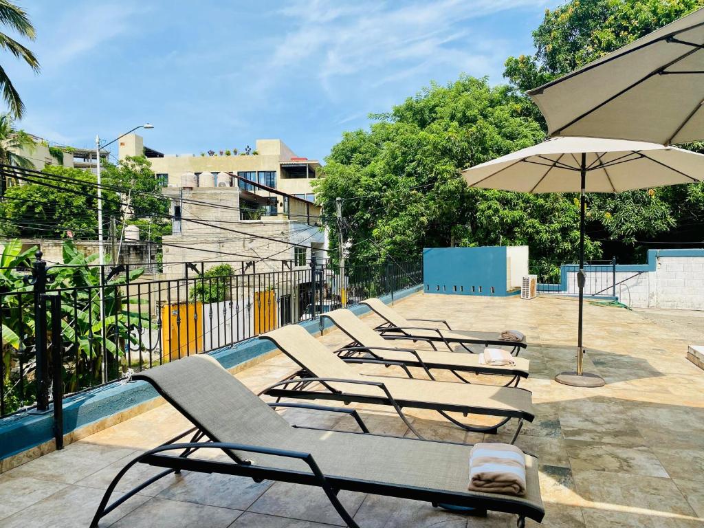 a row of lounge chairs and an umbrella on a patio at casa mexicana en sayulita in Sayulita