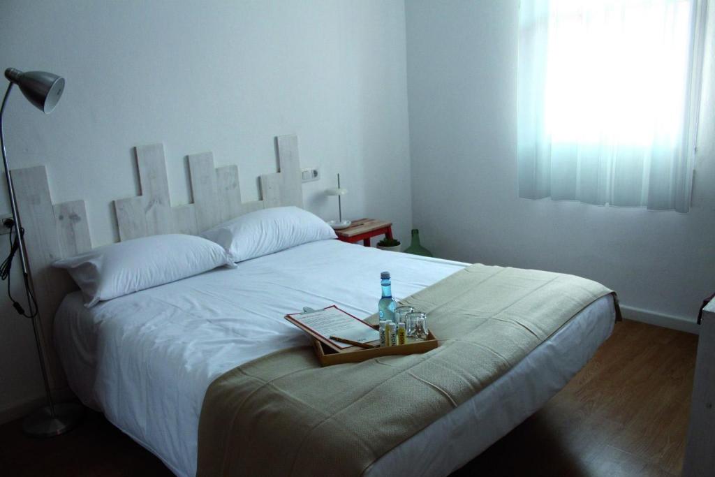 MON ComeySueña Guesthouse في مونفورتي دي ليموس: سرير مع صينية عليها زجاجة ماء