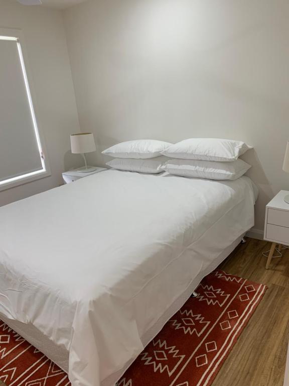 1 Schlafzimmer mit 2 Betten mit weißer Bettwäsche und einem roten Teppich in der Unterkunft P & C On Catherine in Port Macquarie