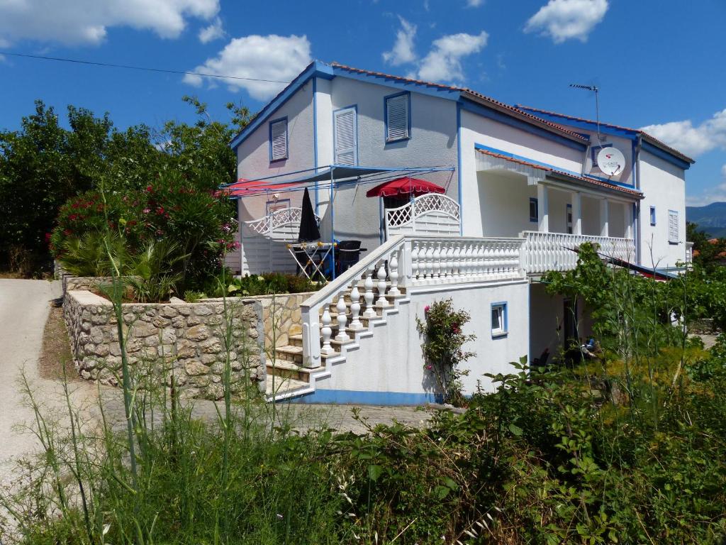 ein blau-weißes Haus mit einer Treppe und einem Regenschirm in der Unterkunft Apartments Different Colours in Šilo