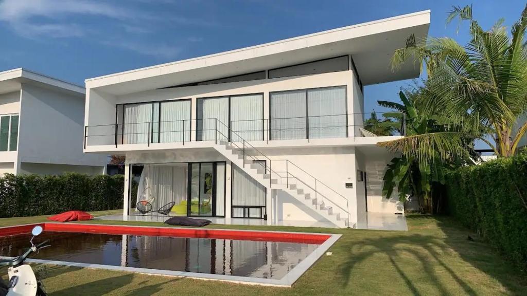 a large white house with a swimming pool in front of it at White Lagoon in Hua Hin