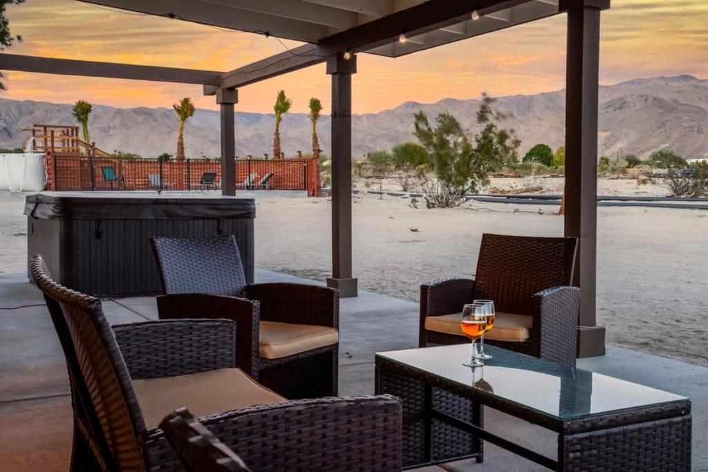 a patio with a table and chairs and a glass of wine at Ranch House with Lap Pool Biking & Running Course in Desert Hot Springs