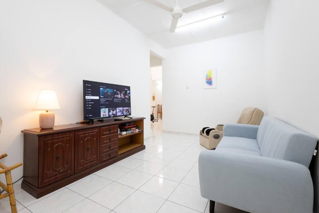 Una sala de estar con un sofá y un televisor de pantalla plana. en Homie4u - Ipoh Garden East 8 pax, en Ipoh