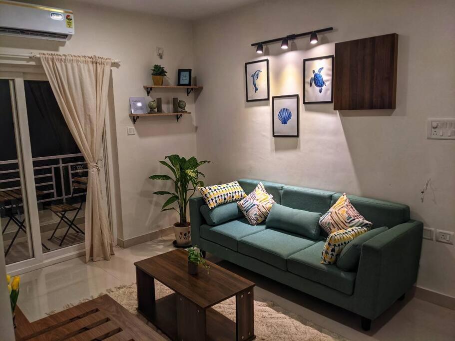un soggiorno con un divano verde e un tavolo di Pednekar's House, 1BHK with pool by SneekoStays a Nerul