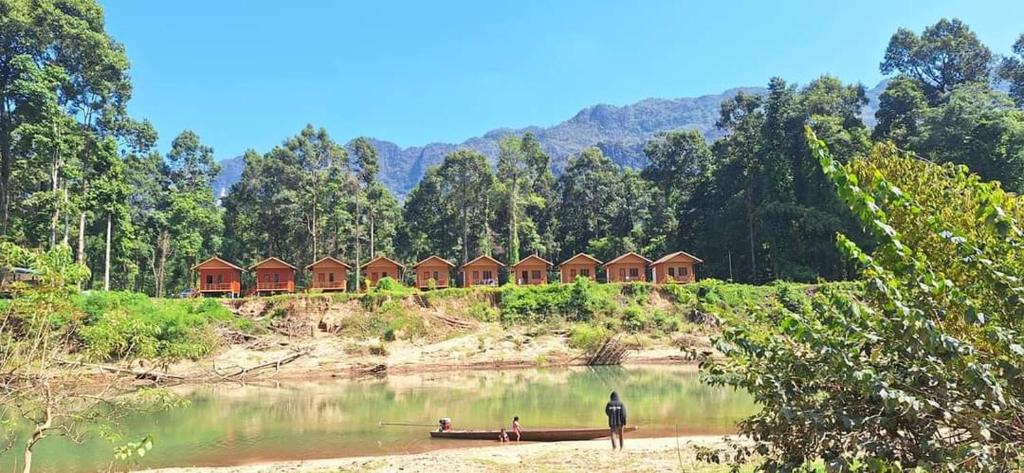 a man standing in the water in front of a house at Konglor Cave Resort-Riverside Restaurant in Ban O