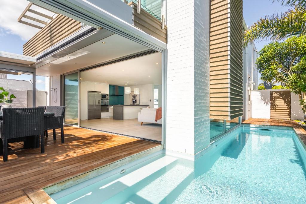 an open patio with a swimming pool next to a house at Beachside Retreat with Private Pool in Papamoa