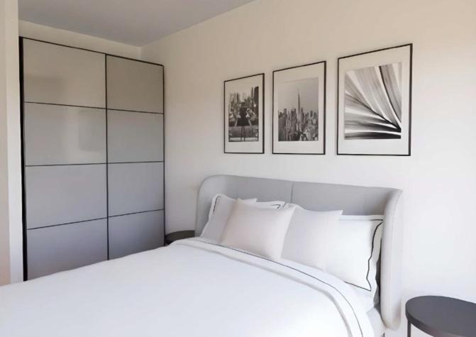 a bedroom with a white bed with three pictures on the wall at Madrid Suites Moncloa-Aravaca, SOLO CHECK IN ON LINE - PARKING GRATUITO in Madrid
