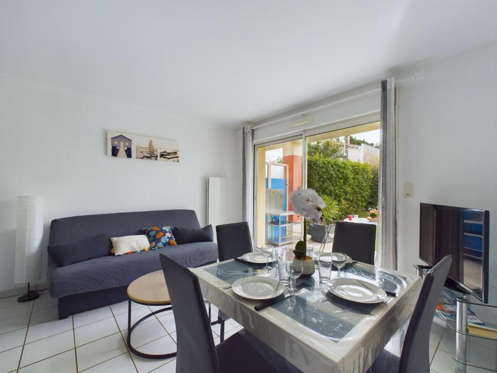 un salon avec une table et un canapé bleu dans l'établissement Les Sables d'Olonne - appartement pour 4 et jardin, à Les Sables-dʼOlonne