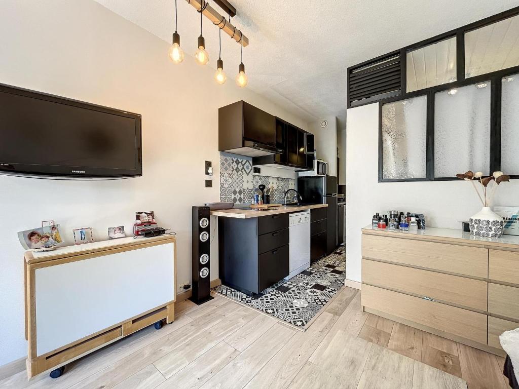 Il comprend une cuisine avec un comptoir et une télévision murale. dans l'établissement T1 très fonctionnel résidence Tennis Village piscine, Ping Pong, citypark, boulodrome, au Cap d'Agde