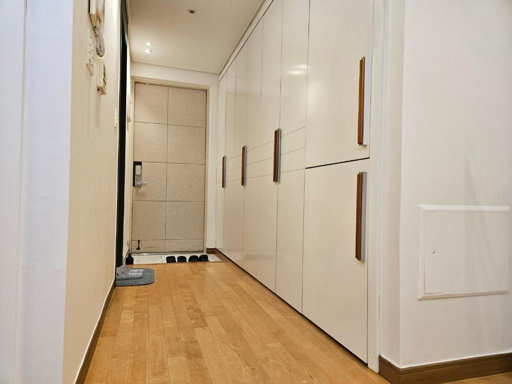 ソウルにあるGangnam Yeoksam Station Full-option Remodeling New Houseの白いキャビネットとハードウッドフロアの廊下