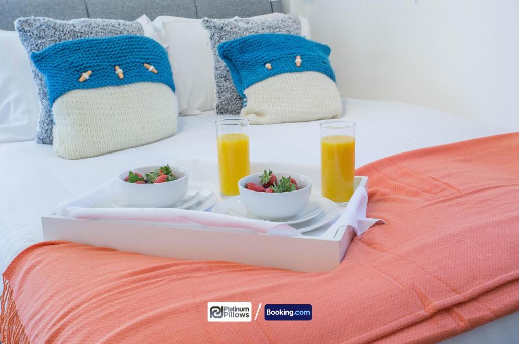 a tray of food on a bed with two glasses of orange juice at Compact 1BR Studio, Fast Wi-Fi & Kitchenette, Great for Short Stays & Monthly Bookings in Little Marlow