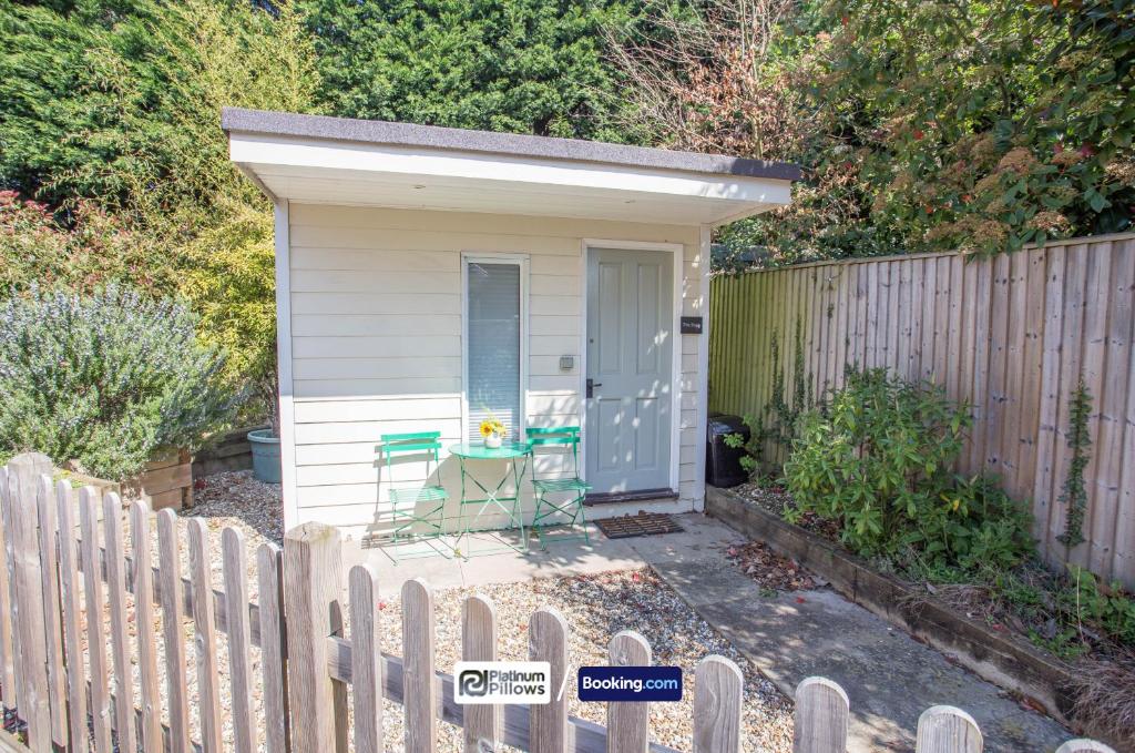 a small shed with a table and a chair next to a fence at Compact 1BR Studio, Fast Wi-Fi & Kitchenette, Great for Short Stays & Monthly Bookings in Little Marlow