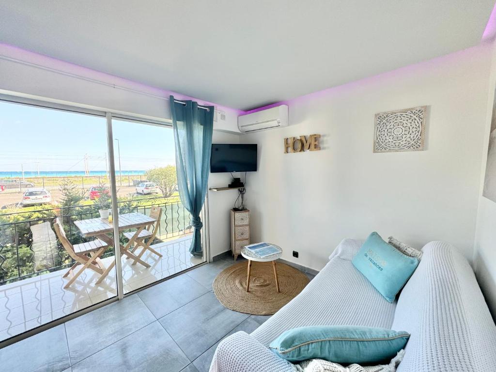 a living room with a couch and a balcony at Le Cocon Marin , vue mer , clim , parking , piscine in Antibes
