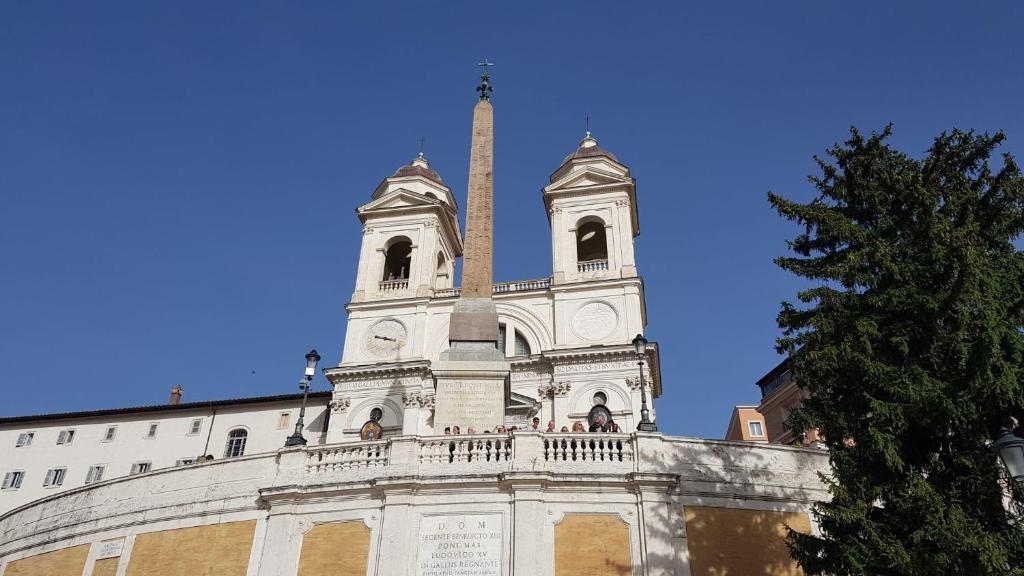 a tall building with a tower and a tree at L'obelisque maison de luxe in Rome