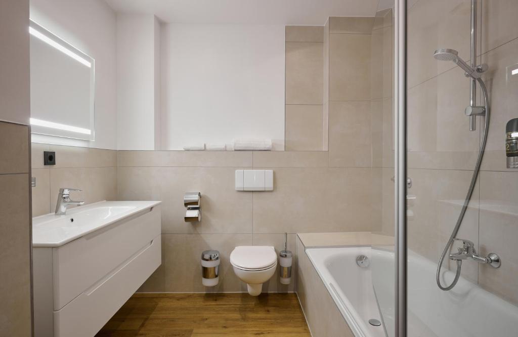 a bathroom with a sink and a toilet and a shower at Leonardo Boutique Hotel Munich in Munich