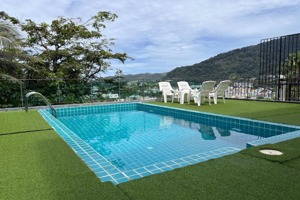 a swimming pool with white chairs at JZ Patong in Patong Beach