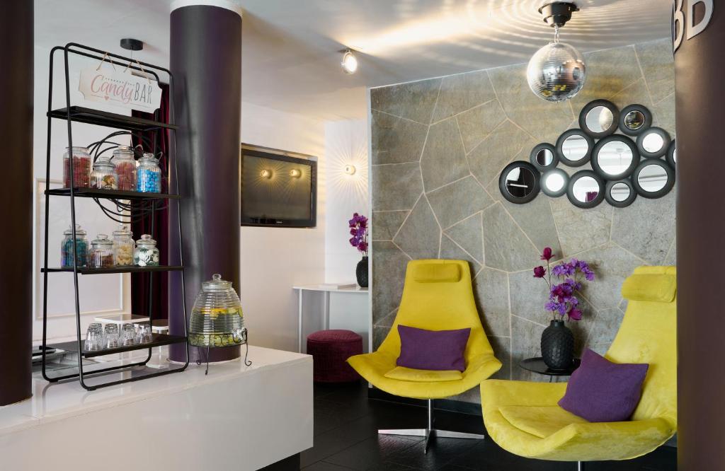 a salon with two yellow chairs and purple pillows at Leonardo Boutique Hotel Munich in Munich