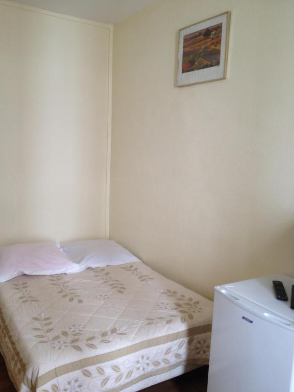a small bedroom with a bed and a small refrigerator at Au Royal Mad in Paris