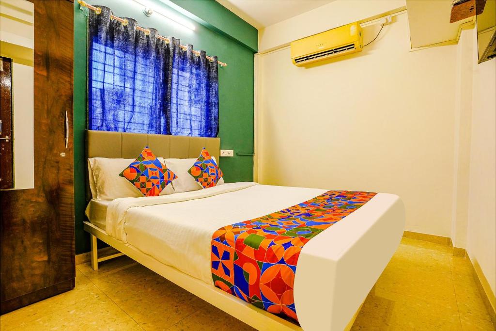 a bedroom with a bed with colorful sheets and a window at FabHotel Diamond Stay in Pune