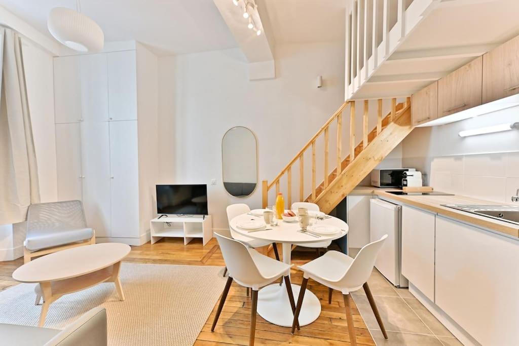 - une cuisine avec des tables blanches et des chaises blanches dans la chambre dans l'établissement Superbe Loft Central #Marais #Rivoli - II, à Paris
