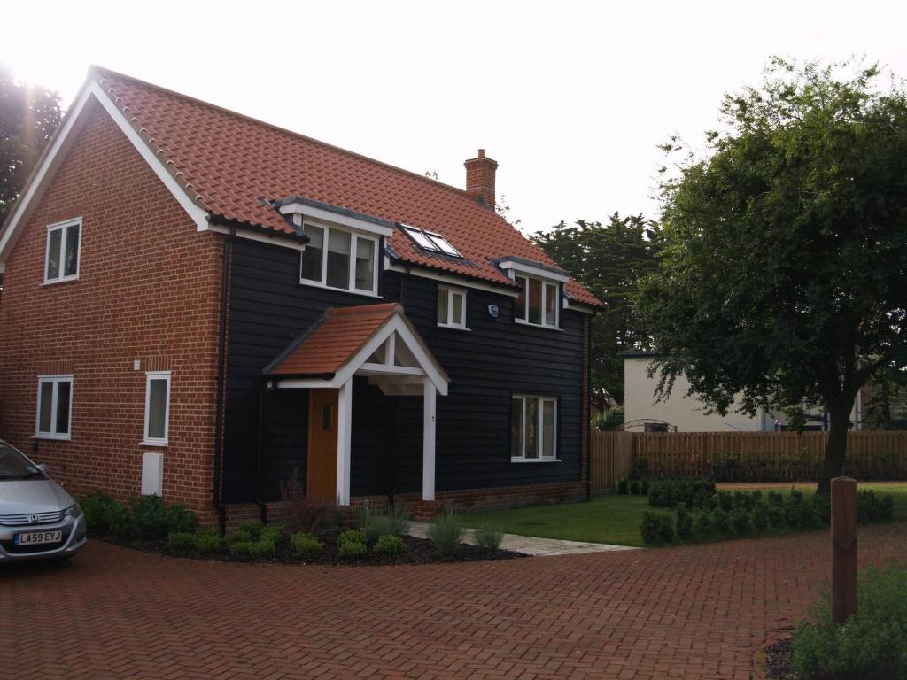 una casa negra con un coche aparcado delante de ella en 3 Alexandra Place, Walberswick, en Walberswick