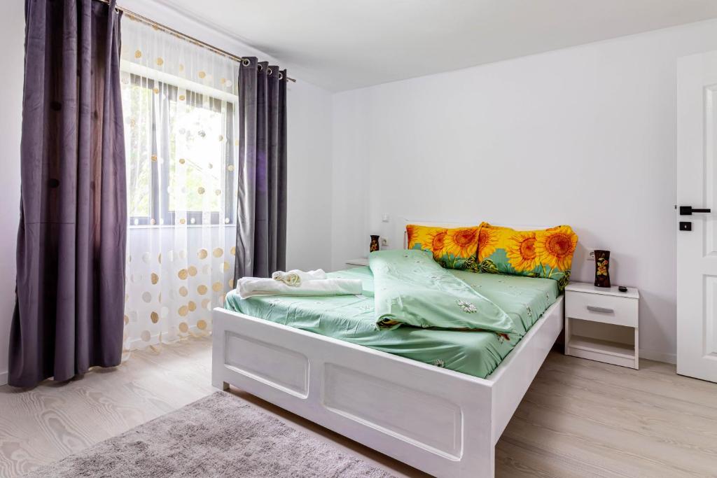 una camera bianca con un letto con cuscini colorati di Casa Andra si Denis a Novaci-Străini