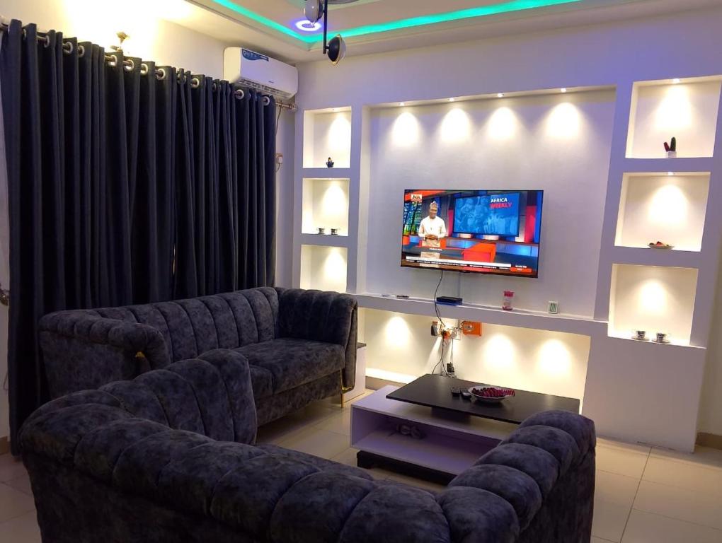 a living room with two couches and a flat screen tv at 2 Bed - Sleeps 4 - AirCon - Free Parking in Benin City