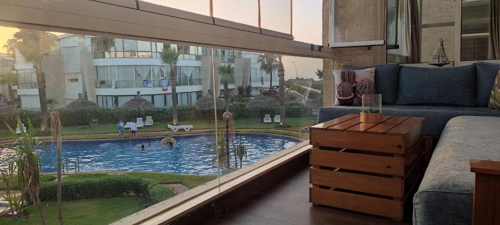 ein Wohnzimmer mit Couch und Swimmingpool in der Unterkunft Les perles de Tamaris in Dar Mohammed Ould Haj Jilali