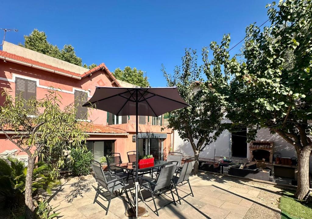 un patio avec une table, des chaises et un parasol dans l'établissement Casa Terra Rossa Le confort créatif au cœur de Marseille, à Marseille