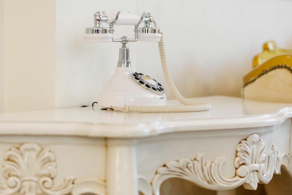 Close-up of white vintage rotary-style telephone resting on carved white dressing table.