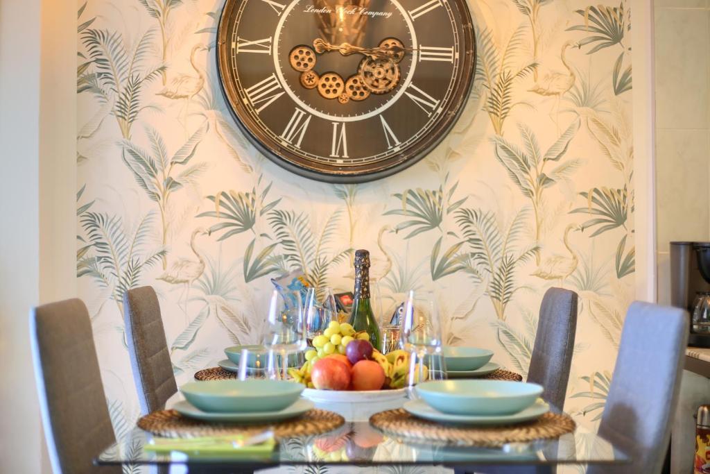a clock on a wall above a table with fruit at LUXORY DREAMY SUNSET, SeaFront, Direct Access To The Promenade,Wifi,Pool,Free Parking in Los Cristianos