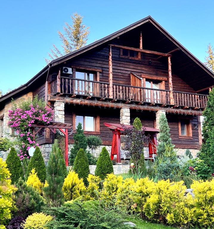 a wooden house with a balcony on top of a garden at Seventh Heaven in Mykulychyn