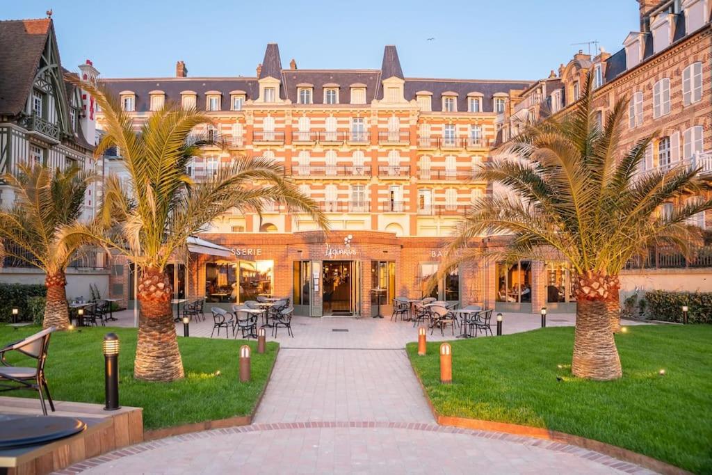 un grand bâtiment avec des palmiers devant dans l'établissement Lumineux Duplex 3chambres 4 personnes & Accès direct à la Plage, à Trouville-sur-Mer