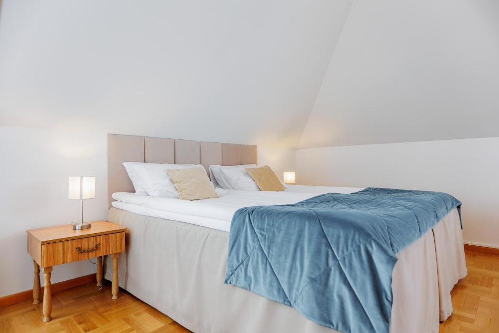 Bright attic double bed with beige headboard, blue throw, bedside lamps, wooden floor.
