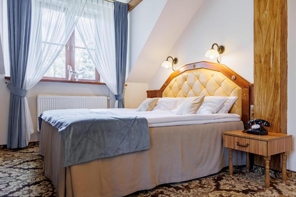 Bright bedroom with beige tufted headboard, grey-blue bed runner, wooden bedside table and vintage phone.