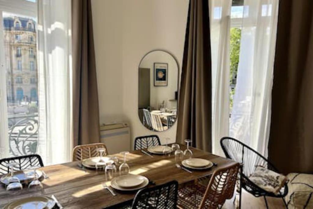 une table de salle à manger avec des chaises et une grande fenêtre dans l'établissement Casa Kûta - Place de la Comédie, Montpellier, à Montpellier